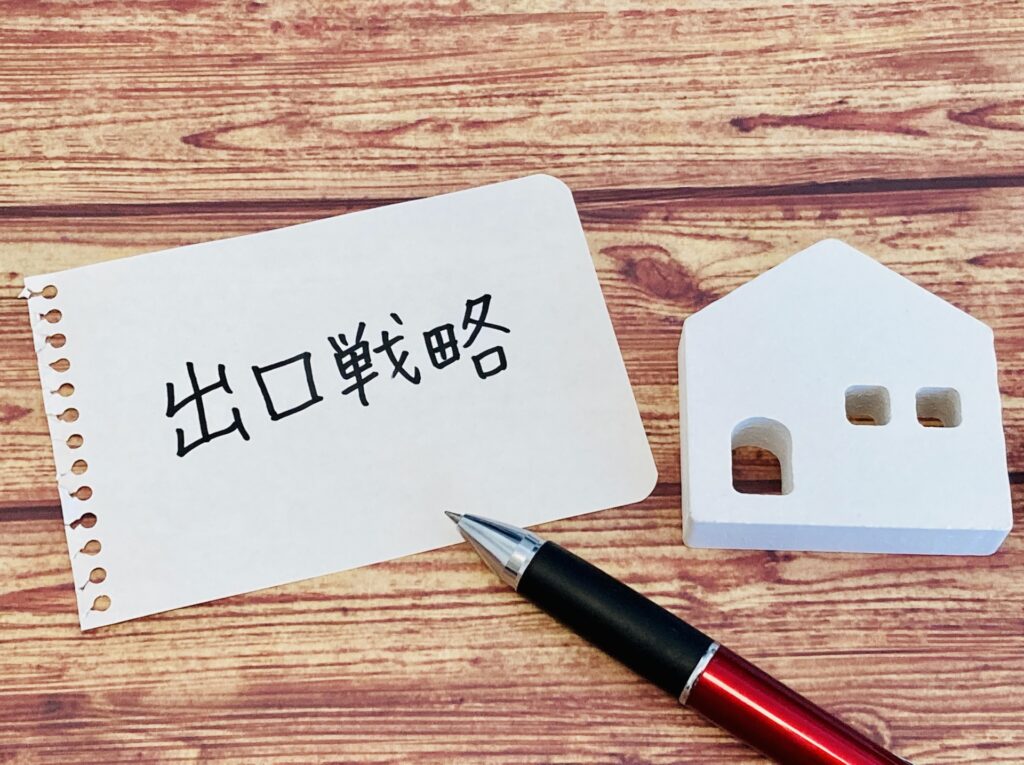 空き家や相続不動産の出口戦略をイメージした写真。住宅模型と「出口戦略」と書かれたメモ。