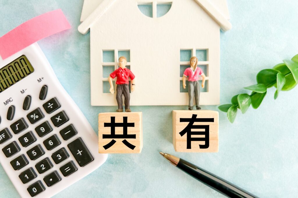 共有不動産をイメージした「共有」の文字と住宅、複数の人物